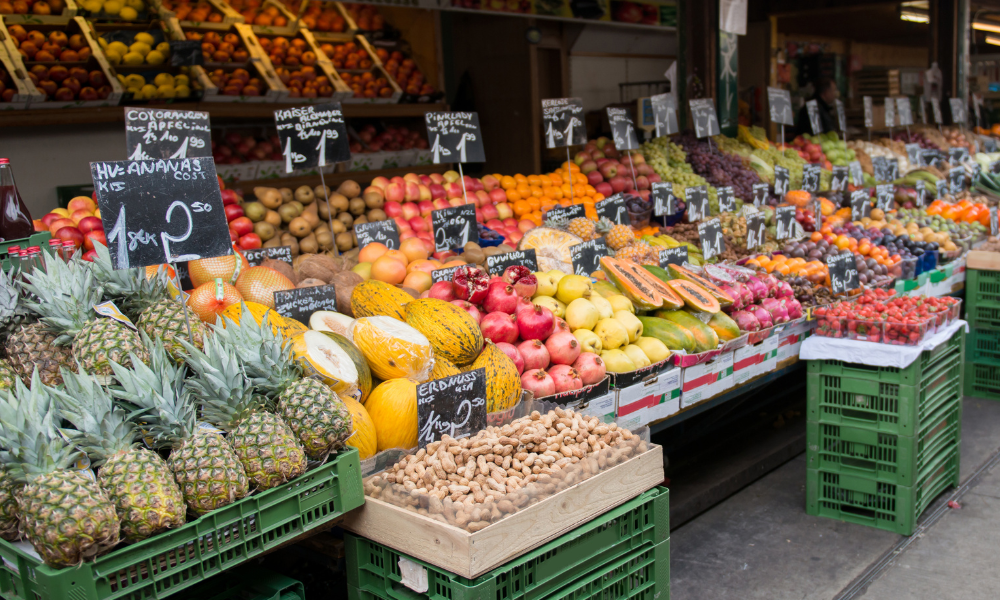 Open-air market stall, vibrant fruit display, neat rows with price tags, bright daytime, editorial travel photo, no people.