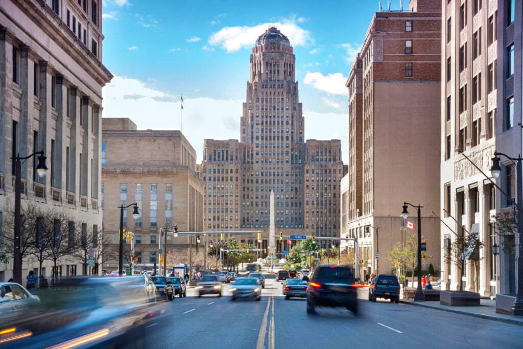 Buffalo City Hall, Art Deco skyscraper, city street and cars, midday sun with clouds, editorial travel photo, no people.