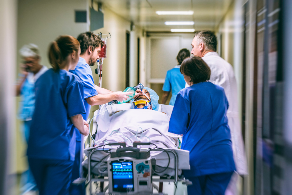 Hospital corridor, patient on gurney, dynamic scene, bright lighting, documentary style, group of medical staff present.