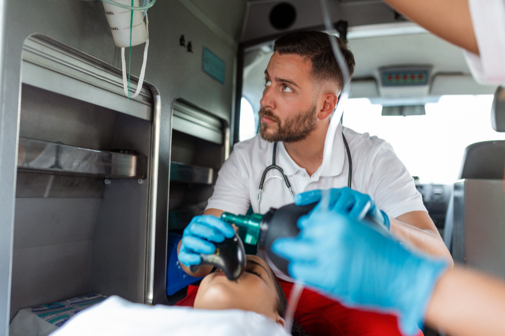 Ambulance interior, paramedic with manual resuscitator center frame, daytime lighting, documentary style, medical tools, people.