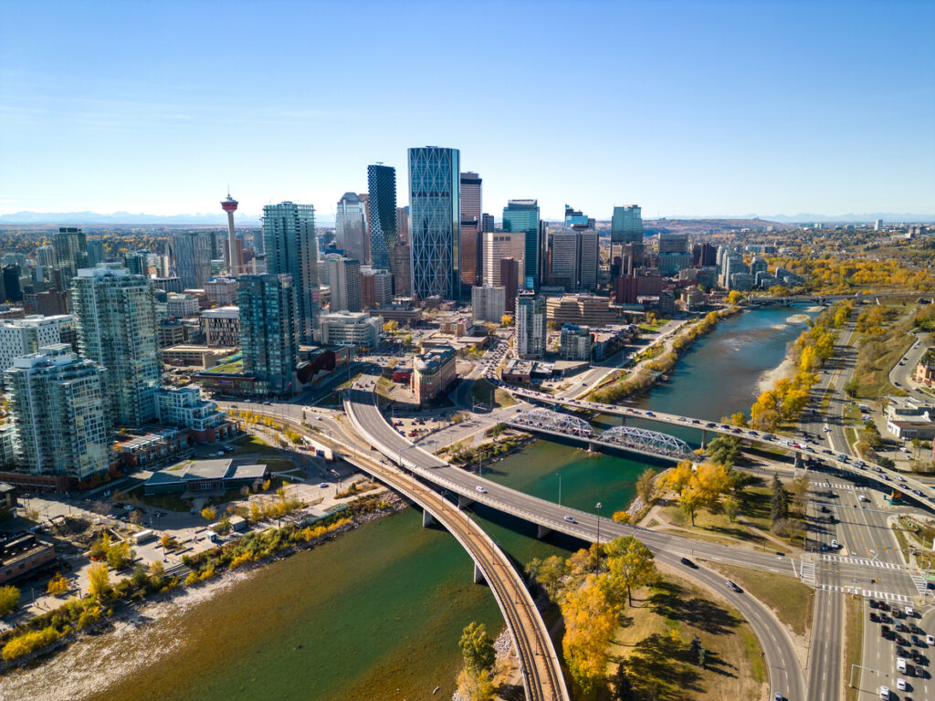 Calgary downtown skyline, modern high-rises, Bow River curves, sunlit afternoon, editorial travel photo, no people.