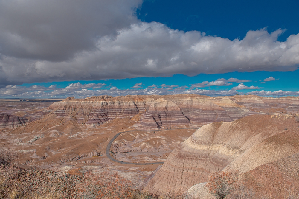 Desert landscape with layered rock formations under a cloudy sky.