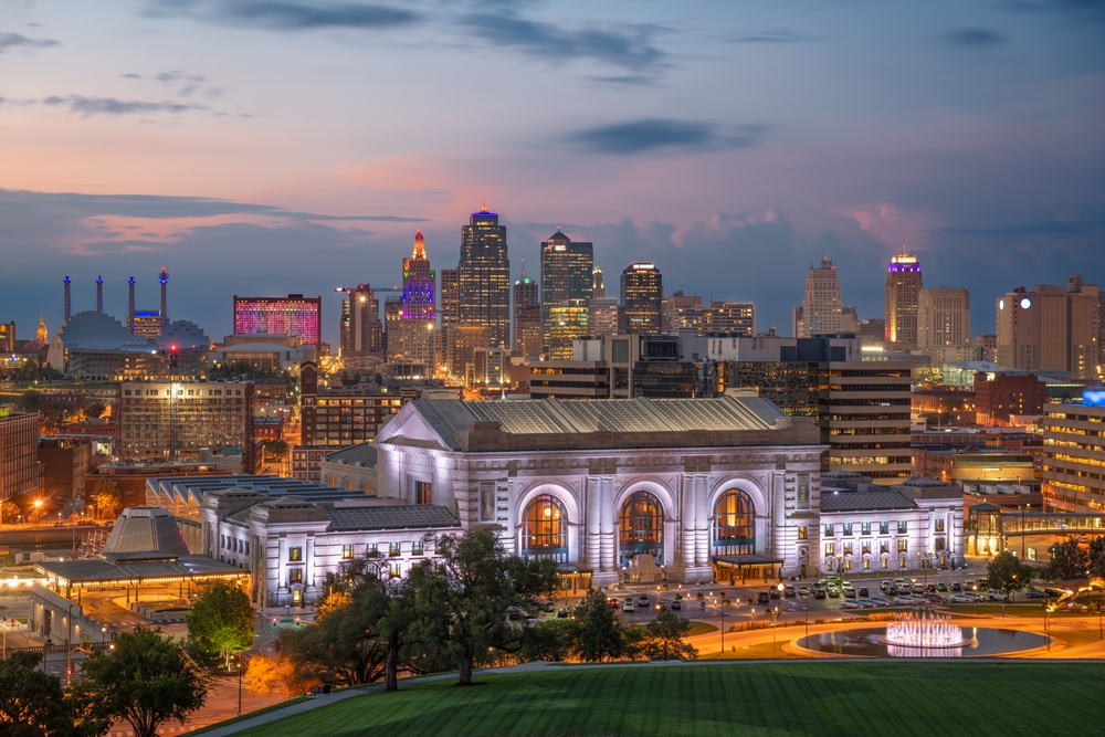Kansas City skyline, Union Station glowing, wide city view at dusk, blue-pink sky, editorial travel photo, no people.
