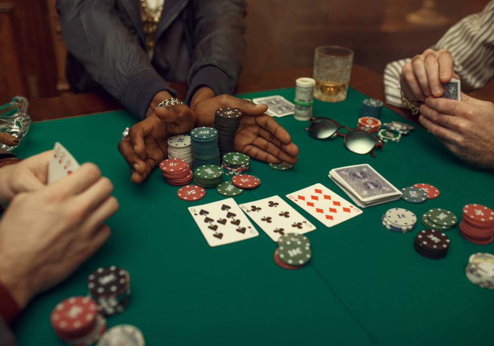 Green poker table, player pushing chips all-in, scattered cards and sunglasses, bright indoor light, documentary style, with people.