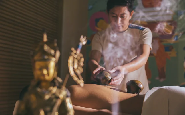 A person applying cupping therapy on a person's back with smoke in the foreground.