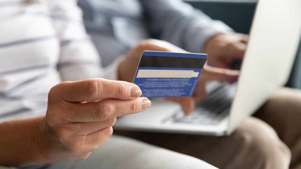 Person holding a credit card while using a laptop.
