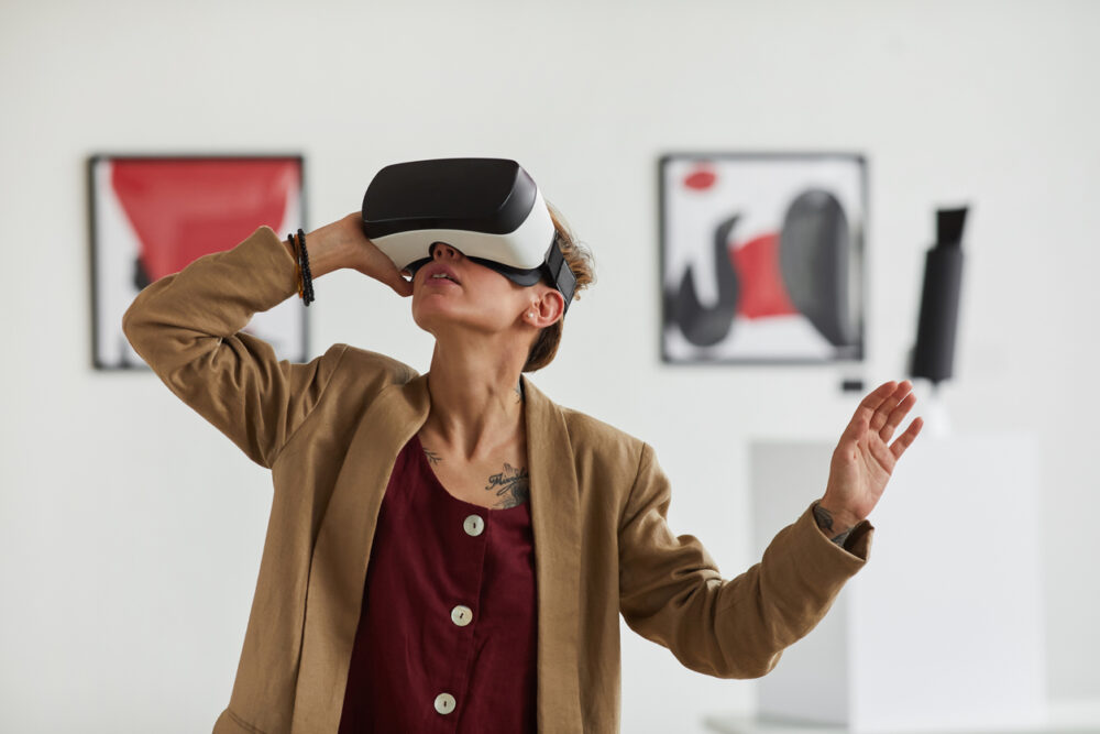 A person wearing a virtual reality headset in an art gallery with abstract paintings on the walls.