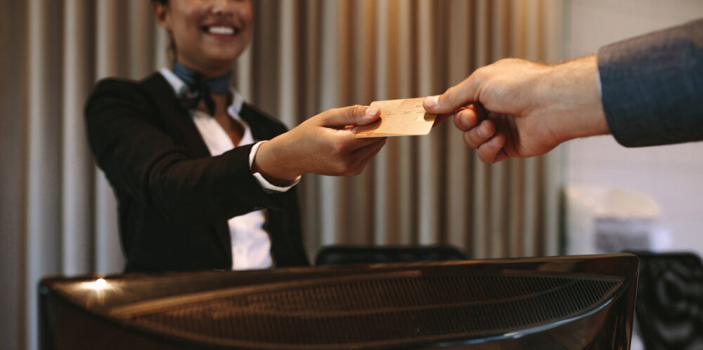 A receptionist hands a credit card to a customer over a desk.
