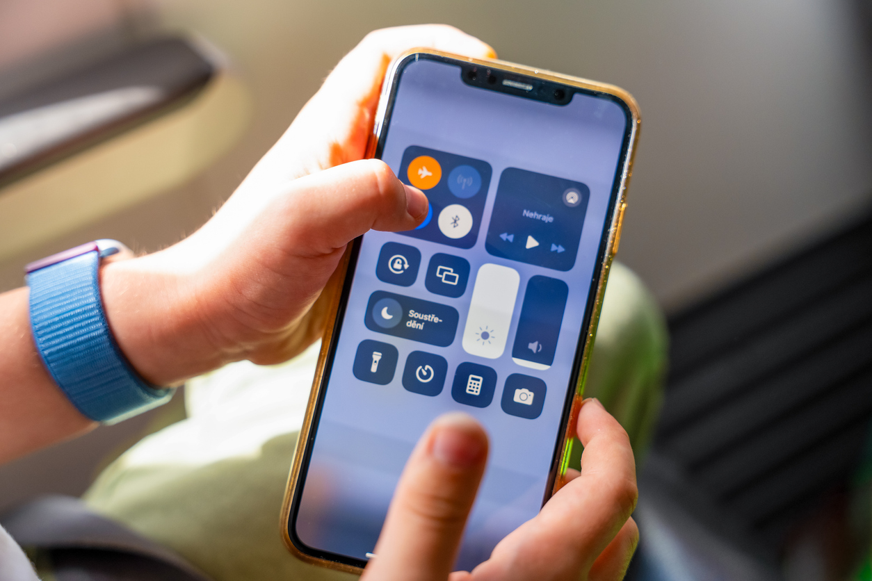 Person holding smartphone displaying the control center screen with various icons.