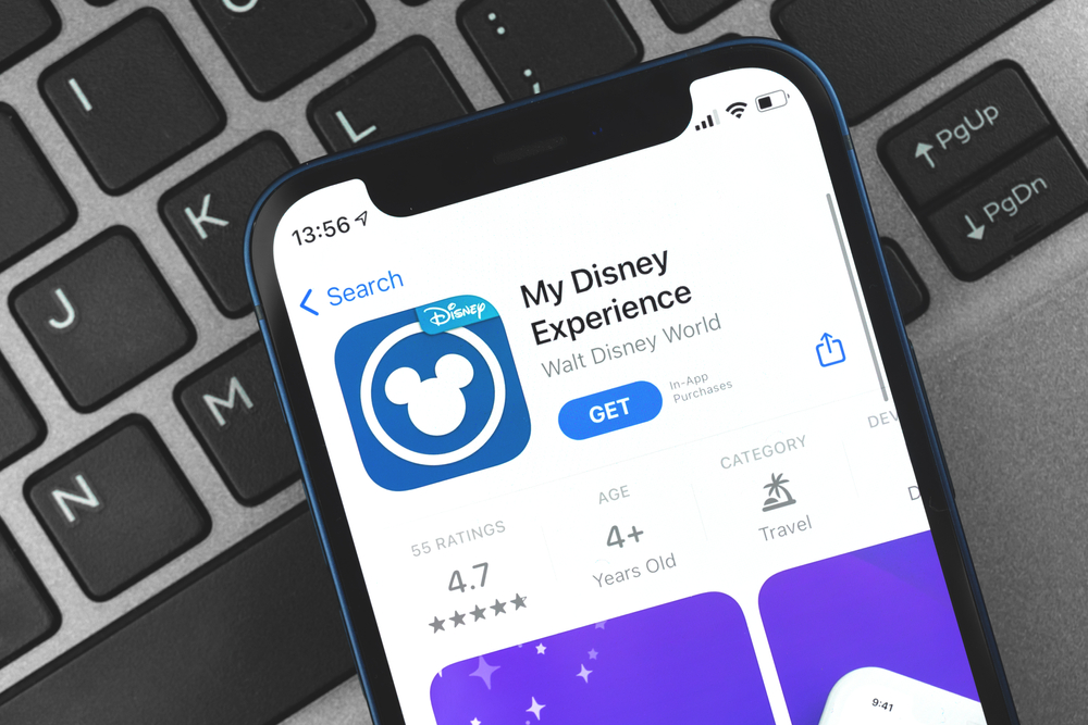 Smartphone displaying "My Disney Experience" app download page on a keyboard background.