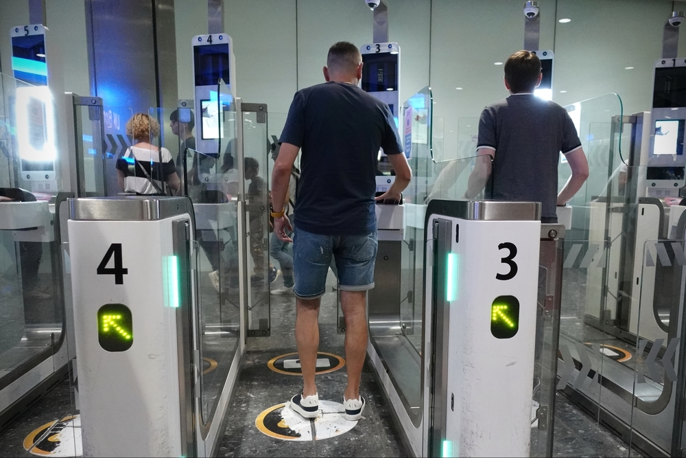 Two men standing at automated airport boarding gates marked with numbers 3 and 4.