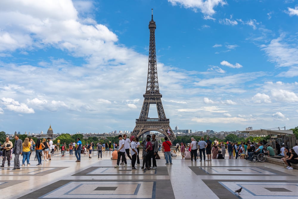 People walking in front of the Eiffel Tower on a cloudy day.